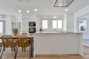 Apartamento El Portet - cocina con isla blanca y mesa de comedor